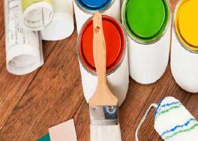 Botes de pintura de colores primarios una brocha y un rodillo de pintar