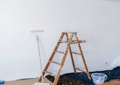 Escalera de madera rodillo de pintar y una pared blanca de fondo